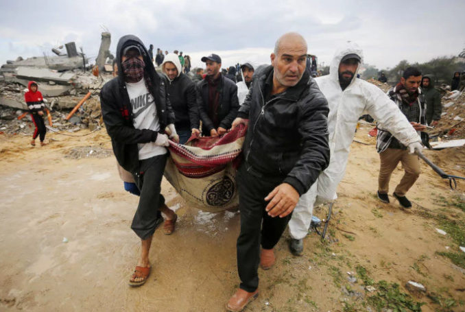 Des Palestiniens transportent un cadavre trouvé sous les décombres alors que les efforts de recherche et de sauvetage se poursuivent dans la zone de la ville d'Az Zawayda de Deir Al Balah, à Gaza, après une frappe aérienne israélienne le 29 janvier 2024 - Photo : Ashraf Amra via Memo